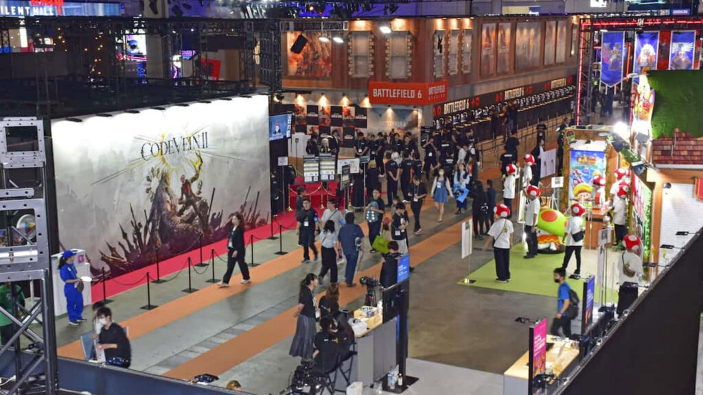 東京ゲームショウの会場。大型のゲームのブースが並ぶ通路を来場者が歩いている写真