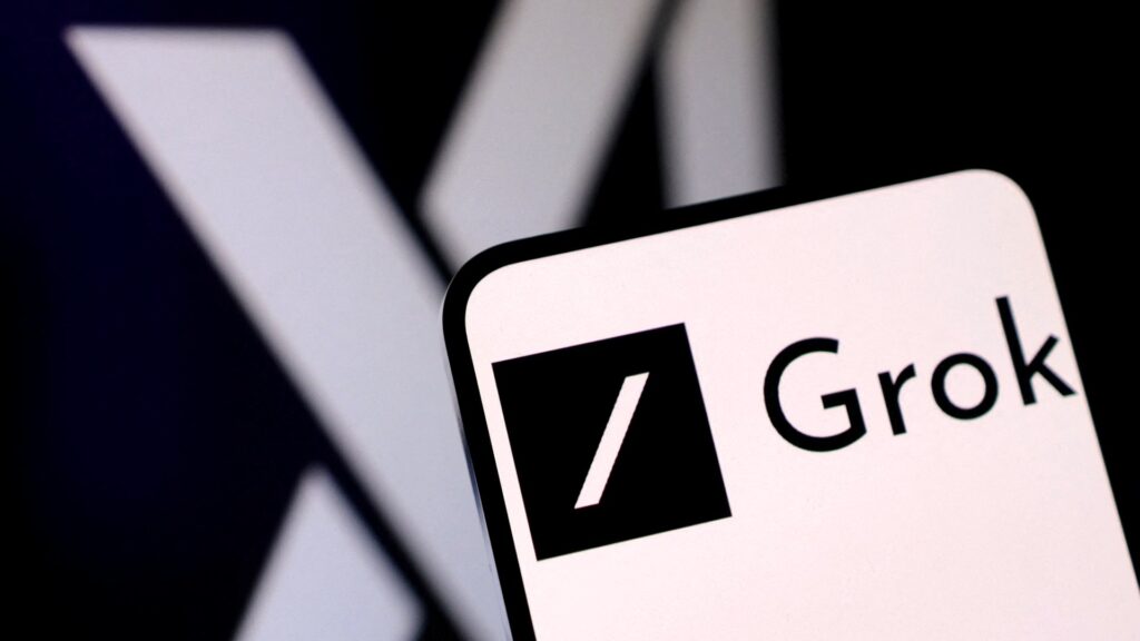 スマートフォンの画面にGrokのロゴが映り、背景に薄くXのロゴが見える写真。6ドルのGrok 4.7は20ドルのGPT-5.6に本当に勝ったか?