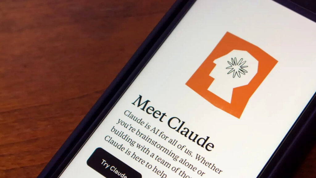 木目のテーブルに置かれたスマートフォンに、ClaudeアプリのMeet Claude画面が表示されている写真