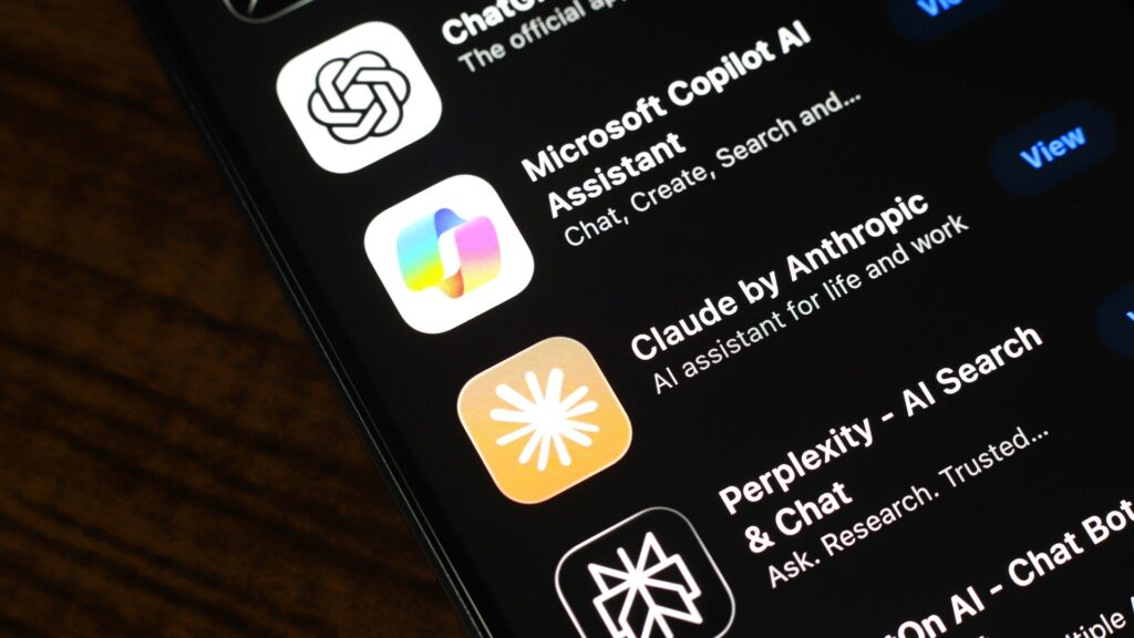 スマートフォンの画面にChatGPT・Microsoft Copilot AI・Claude・Perplexityなど複数のAIアシスタントアプリのアイコンと名称が並んだ一覧の写真。Claude月20ドルにDocsが来てもGoogl…