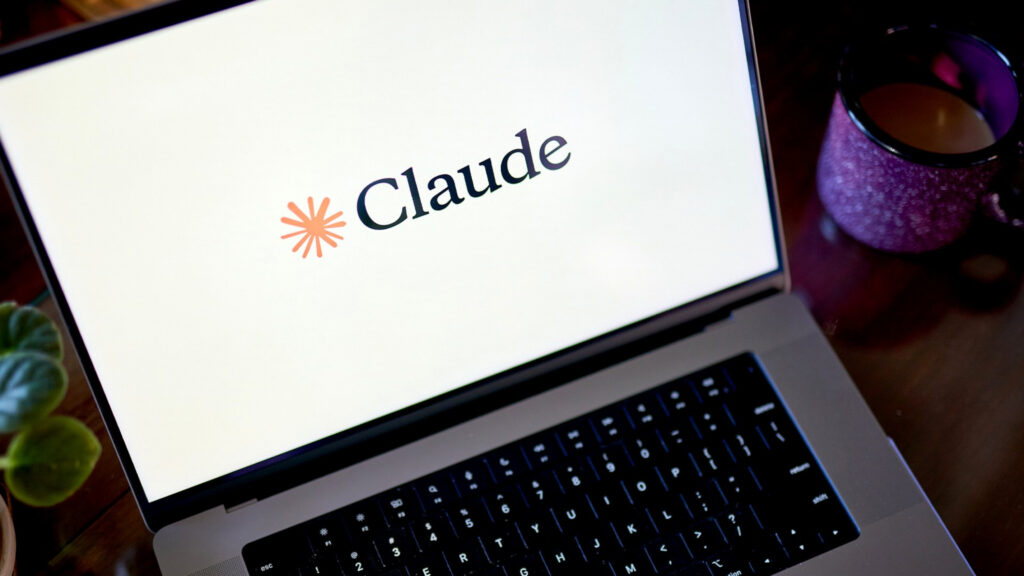 ノートパソコンの画面にClaudeのロゴが表示され、横に紫色のマグカップが置かれている写真