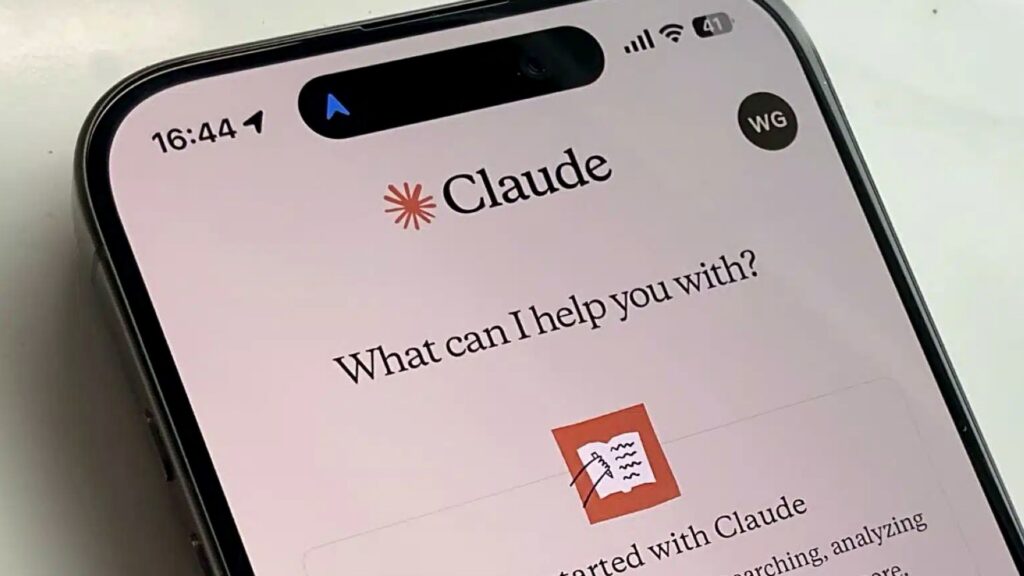 Claudeのチャット画面をiPhoneに表示した白い机の上のスマートフォンの写真。Claude CodeのAIが1体からチームに増えたが月20ドルは要る
