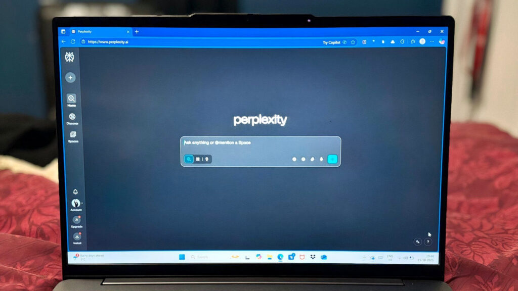 赤いファブリックの上に置かれたノートPCの画面に、Perplexityの検索インターフェースが表示されている写真