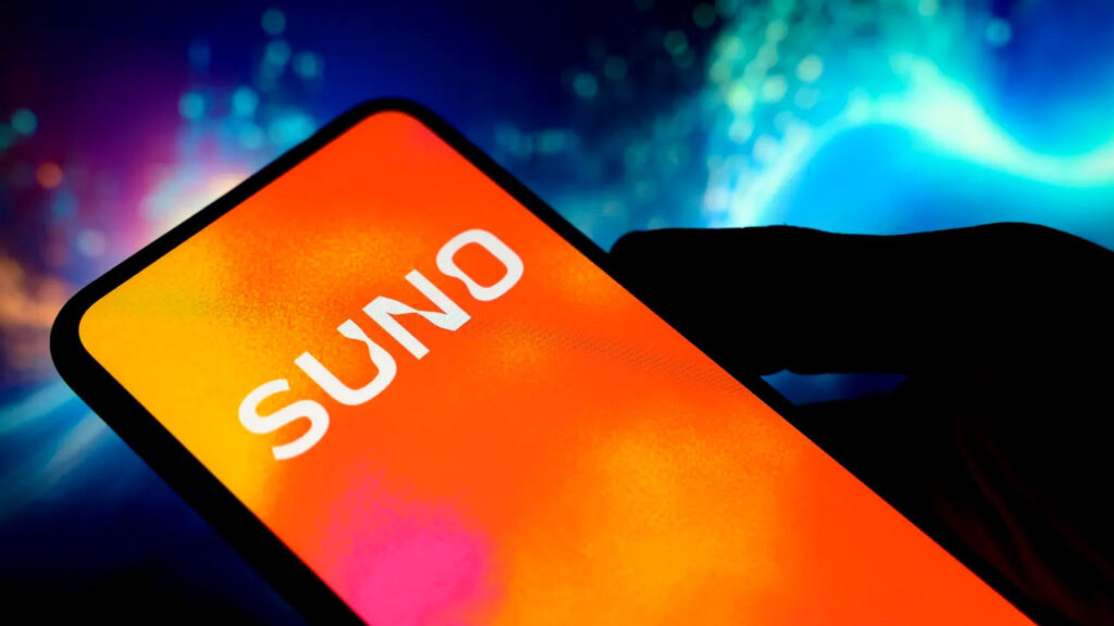 オレンジ色のグラデーション背景にSunoのロゴが表示されたスマートフォンを、手元のシルエットが持っている写真