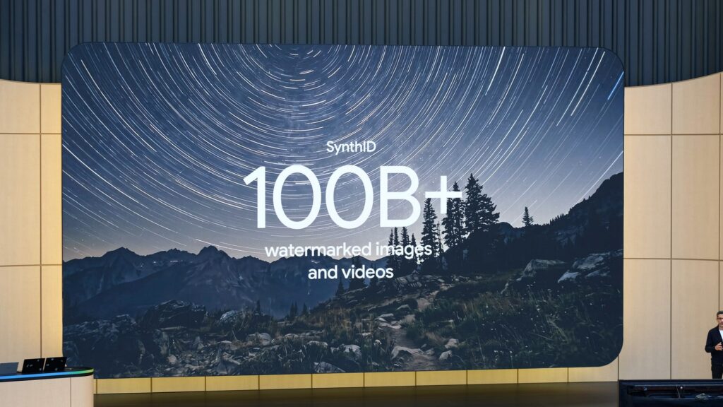 星空の写真を背景にSynthIDと「100B+ watermarked images and videos」の文字が映る大型スクリーンの写真。Google、SynthIDの判定を全員に開放 対象は4社のAIだけだ
