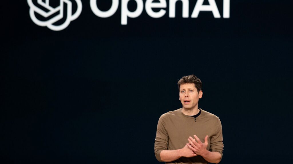 暗い背景に「OpenAI」のロゴがあり、ブラウンのセーターの男性が手を前で組んで話している写真。OpenAI、10月にChatGPTの画像生成で広告を試す 日本は時期未定だ
