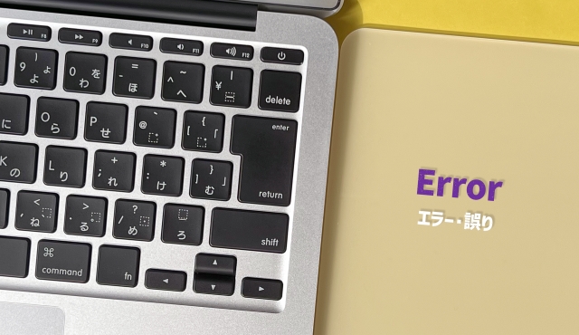 ノートパソコンのキーボードの横の黄色い面に「Error」と「エラー・誤り」の文字を重ねた写真