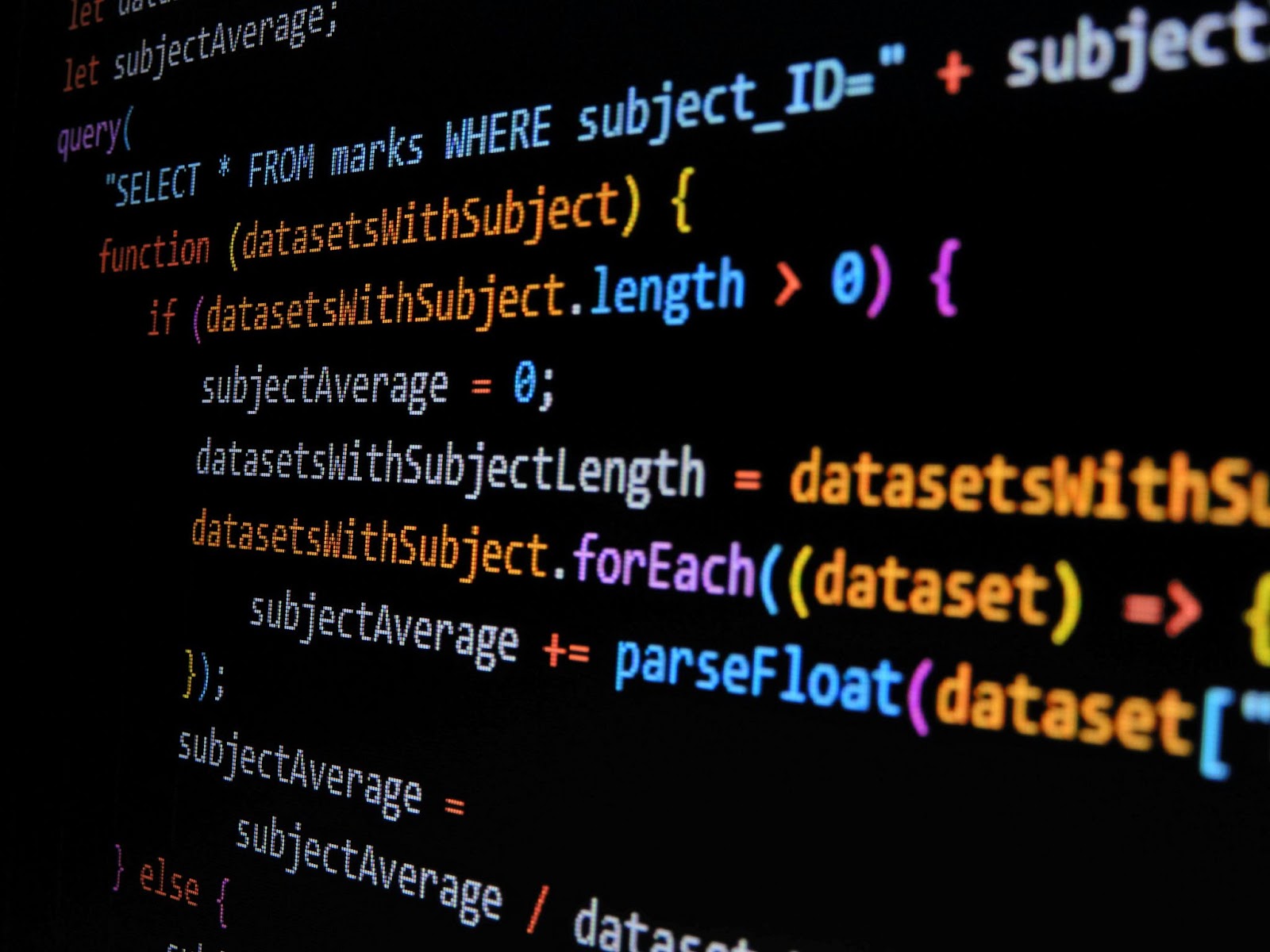 暗い背景に色分けされたJavaScriptのプログラミングコードが並んだ様子を斜めから写した写真