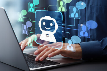 ノートパソコンを打つ両手の上に、笑顔のロボットのアイコンと複数の人物アイコンや吹き出しが浮かんだ写真