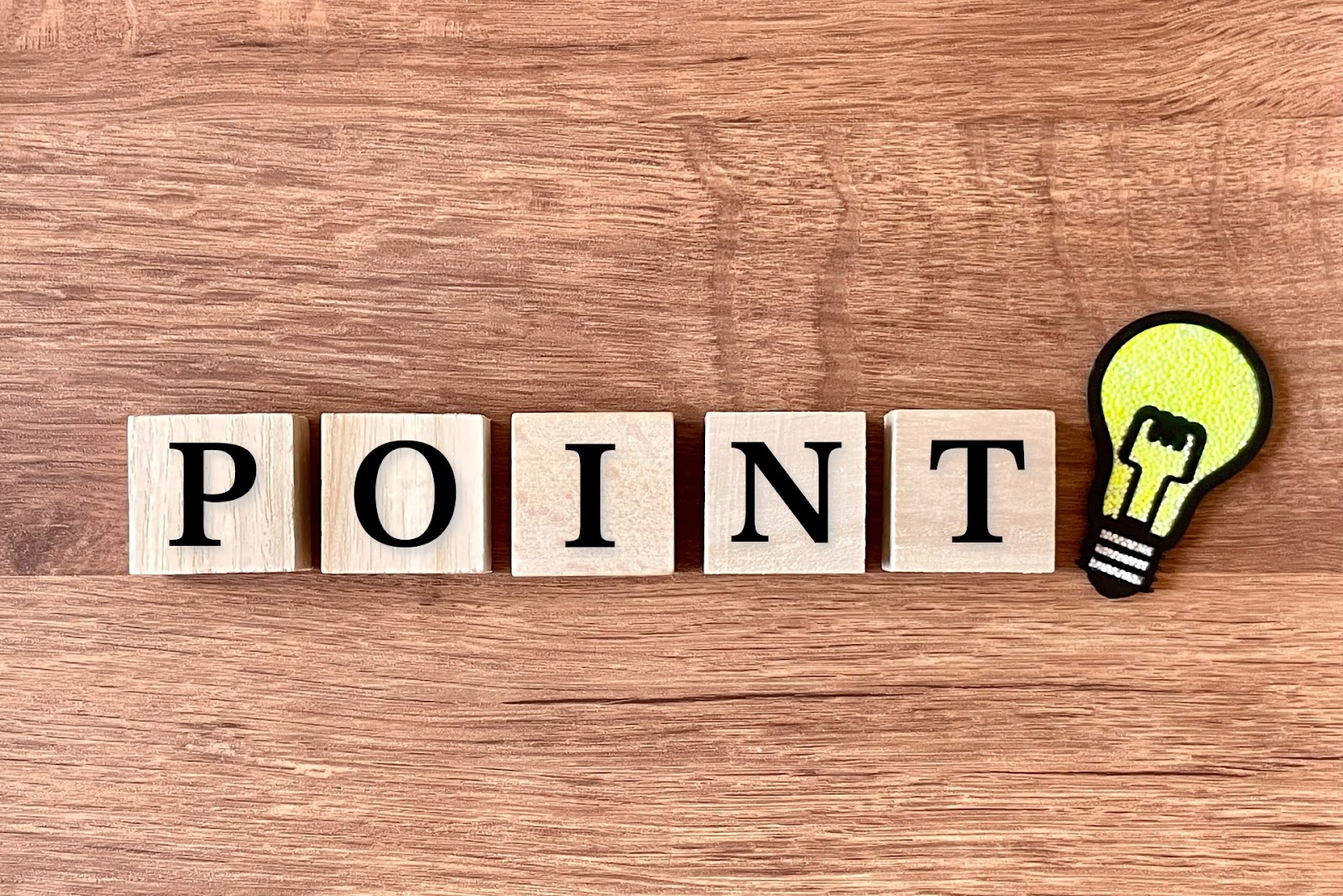 木目の板の上に「POINT」の5文字の積み木と、黄緑色の電球の形のワッペンが並んだ写真