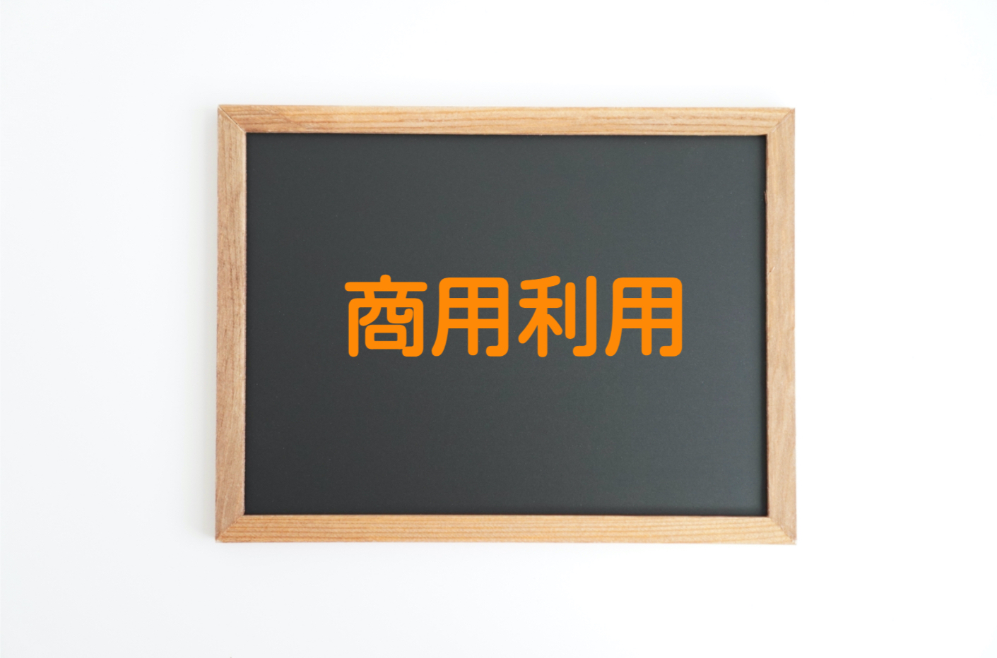 白い背景に置いた茶色い木の枠つきの黒板に、太いオレンジ色の文字で「商用利用」と書かれた写真